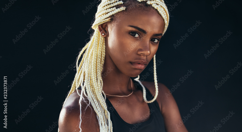 Close up portrait of a female athlete standing against black bac