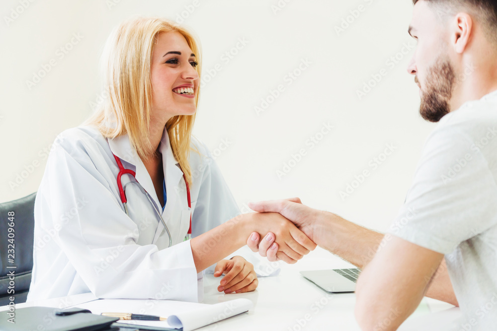 Woman doctor doing handshake with male patient in hospital office room. Healthcare and medical servi