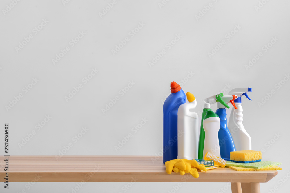 Cleaning supplies on wooden table against light background