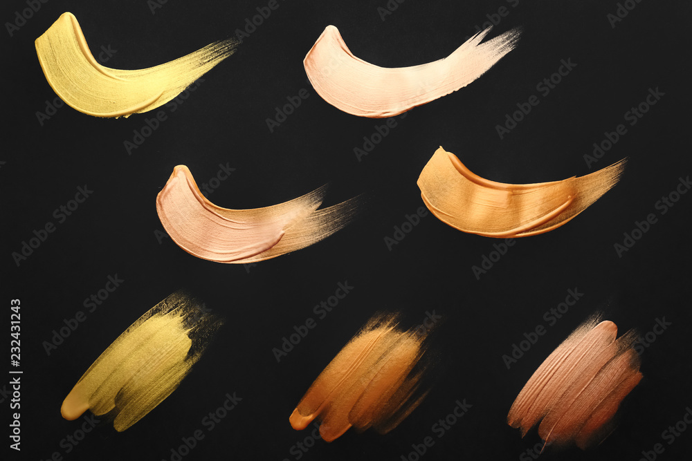 Strokes of different gold paints on dark background