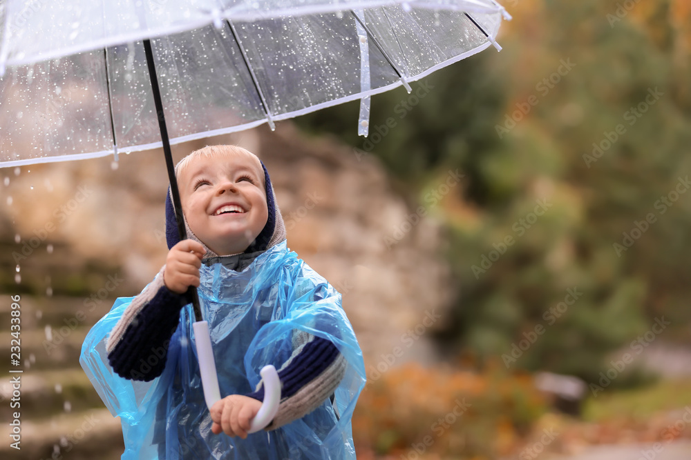 可爱的小男孩，带着透明雨伞，在户外淋雨