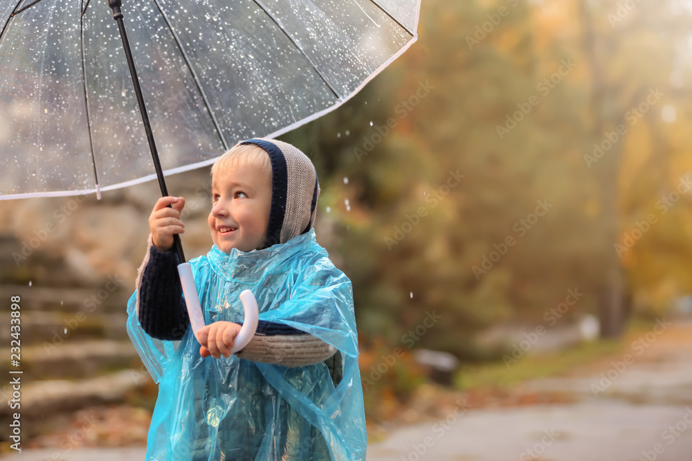 可爱的小男孩，带着透明雨伞，在户外淋雨