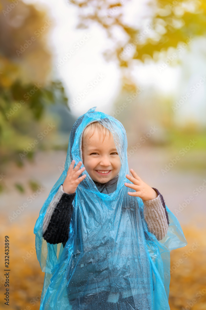 Cute little boy in raincoat having fun in autumn park