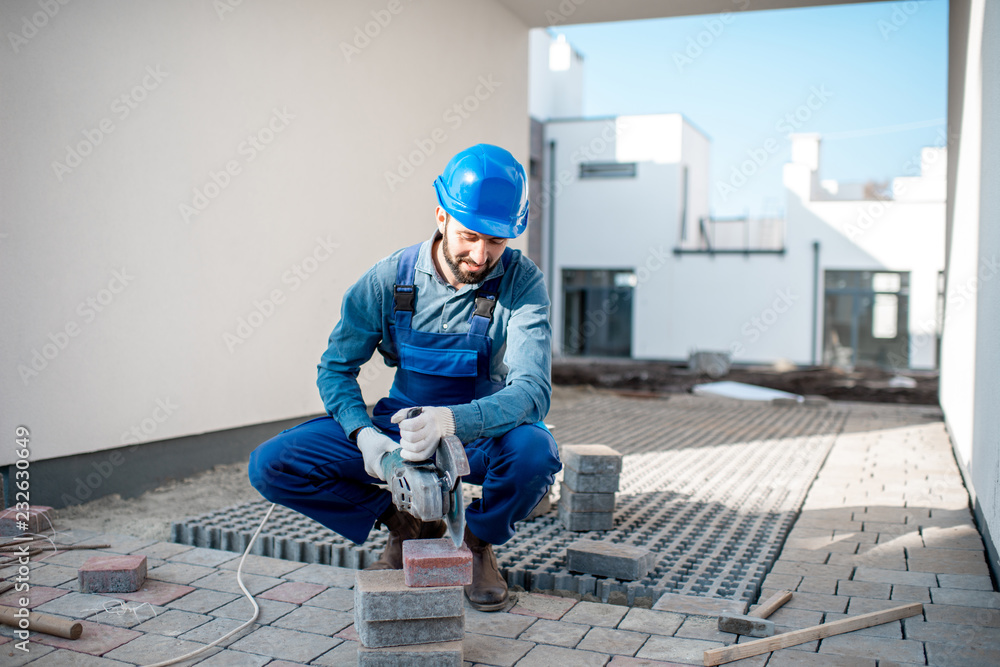 建筑工地上用电动切割机均匀切割铺路砖的建设者