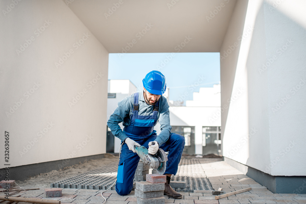 建筑工地上用电动切割机均匀切割铺路砖的建设者