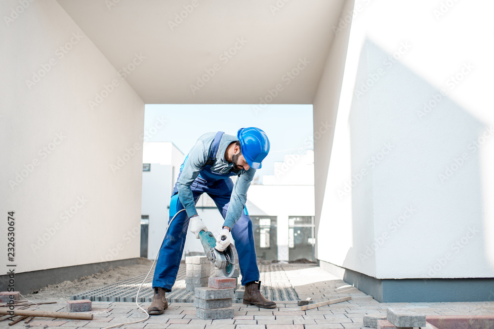 建筑工地上用电动切割机均匀切割铺路砖的建设者