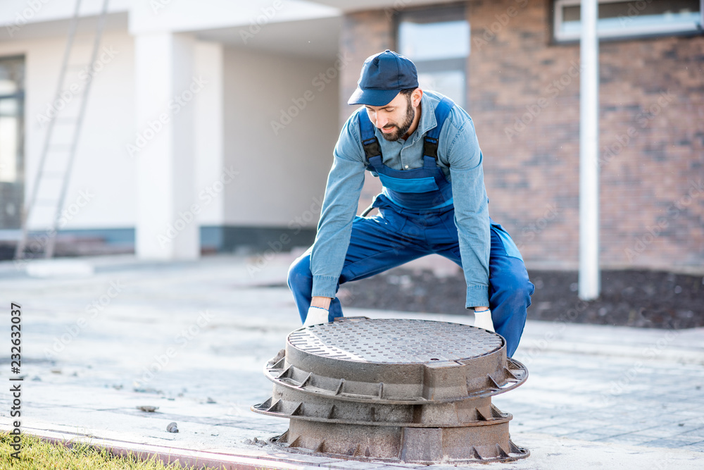 穿着制服的工人在住宅区安装新的道路舱口