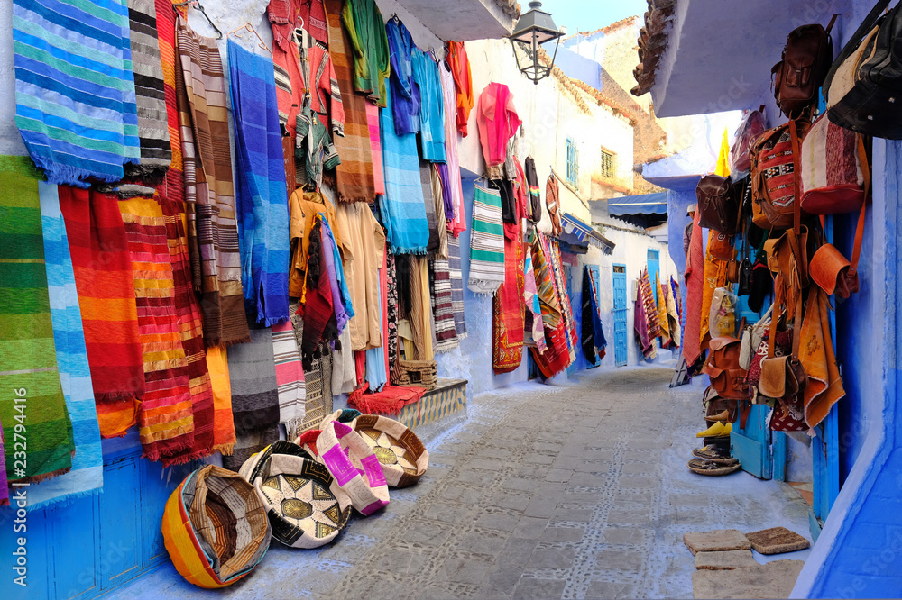 Moroccan handmade crafts, carpets and bags hanging in the narrow street of Essaouira in Morocco with