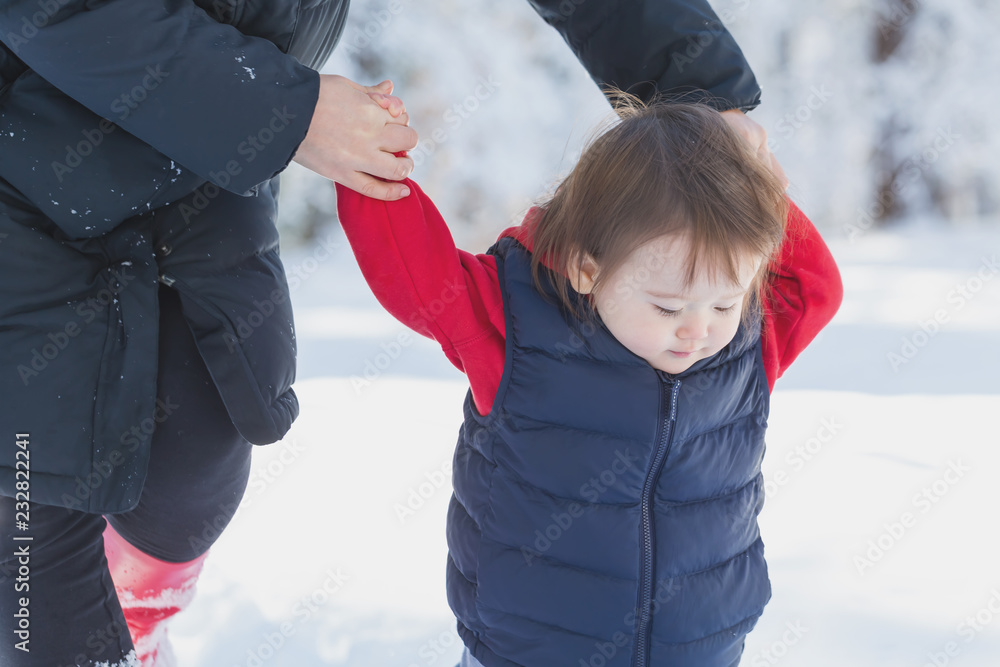 蹒跚学步的男孩和妈妈在雪地里玩耍