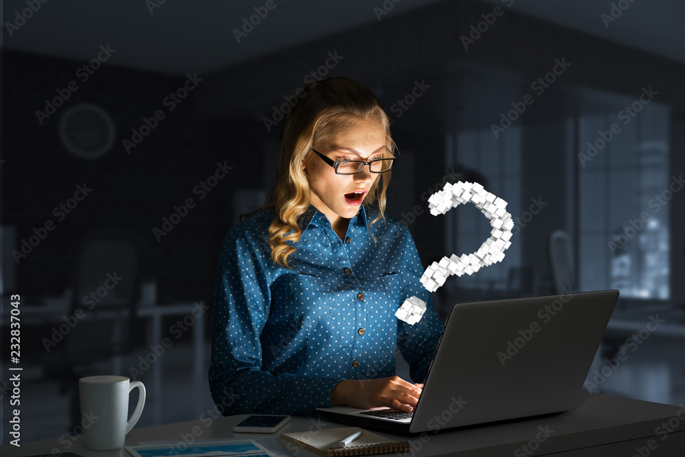 Attractive blonde wearing glasses in dark office using laptop. Mixed media