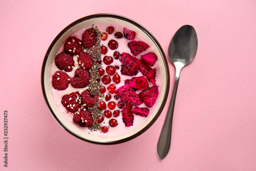 Yogurt with berries and cut dragon fruit in bowl on color background