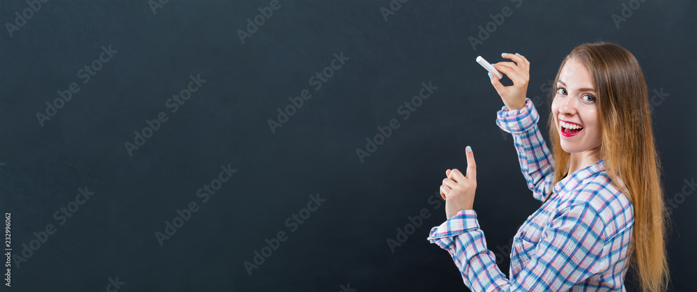 Young woman writing on a black chalkboard