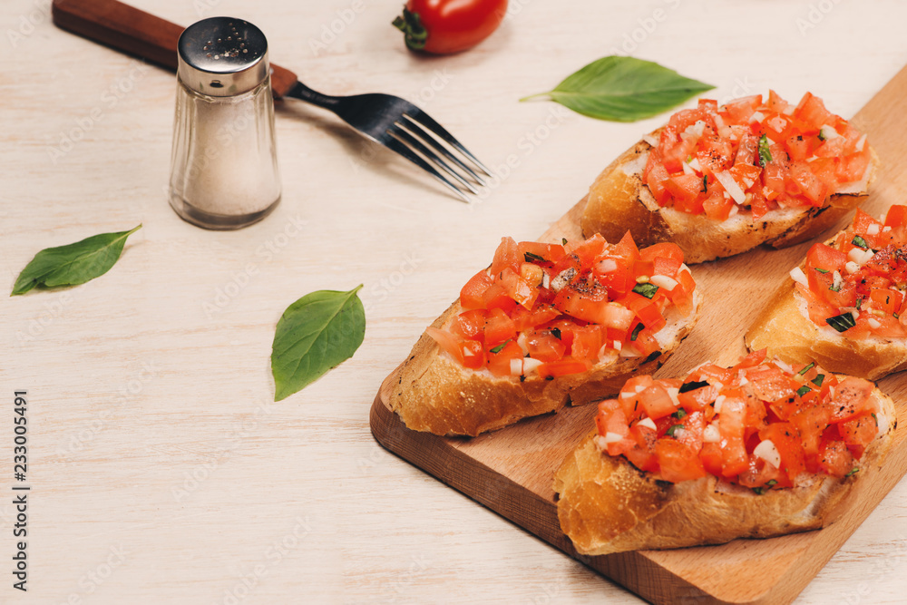 Tasty Italian bruschetta with  bread topped with tomato and herbs on wooden board