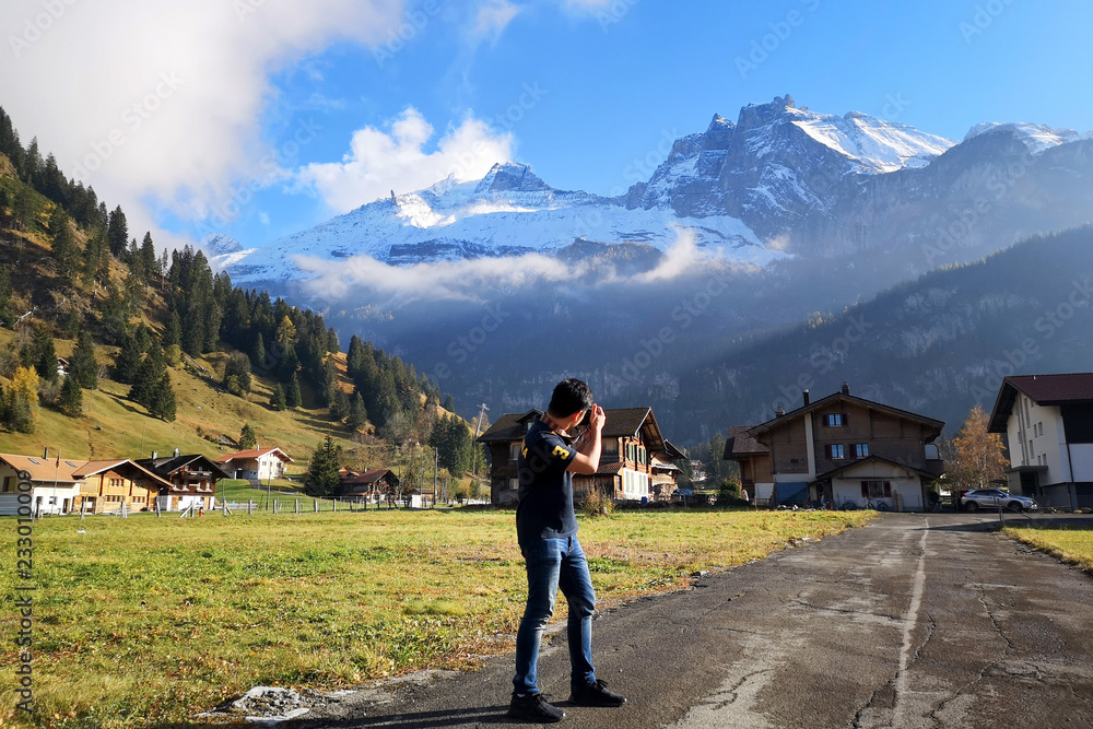 旅行者站着拍摄坎德斯特格阿尔卑斯山和村庄的景观。