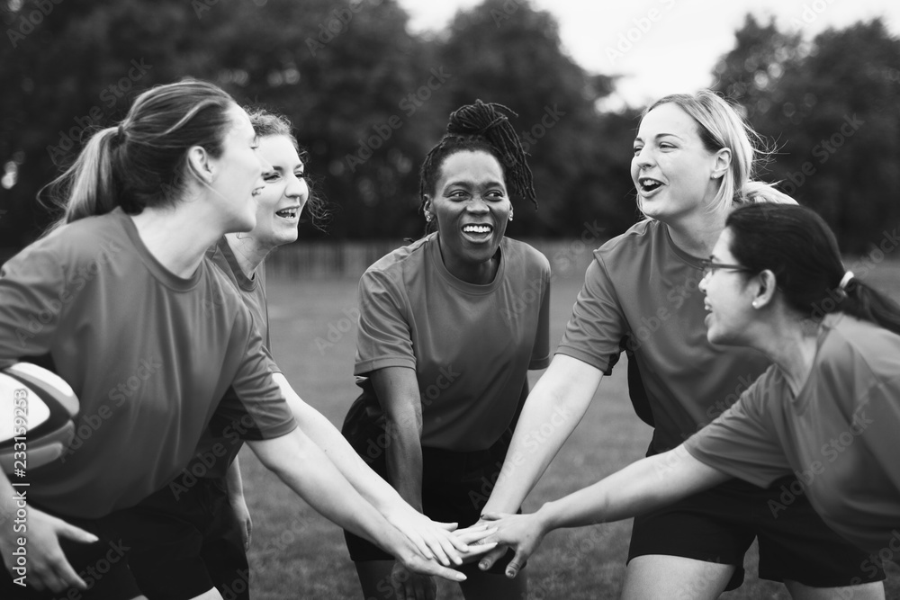 Female rugby players stacking their hands together