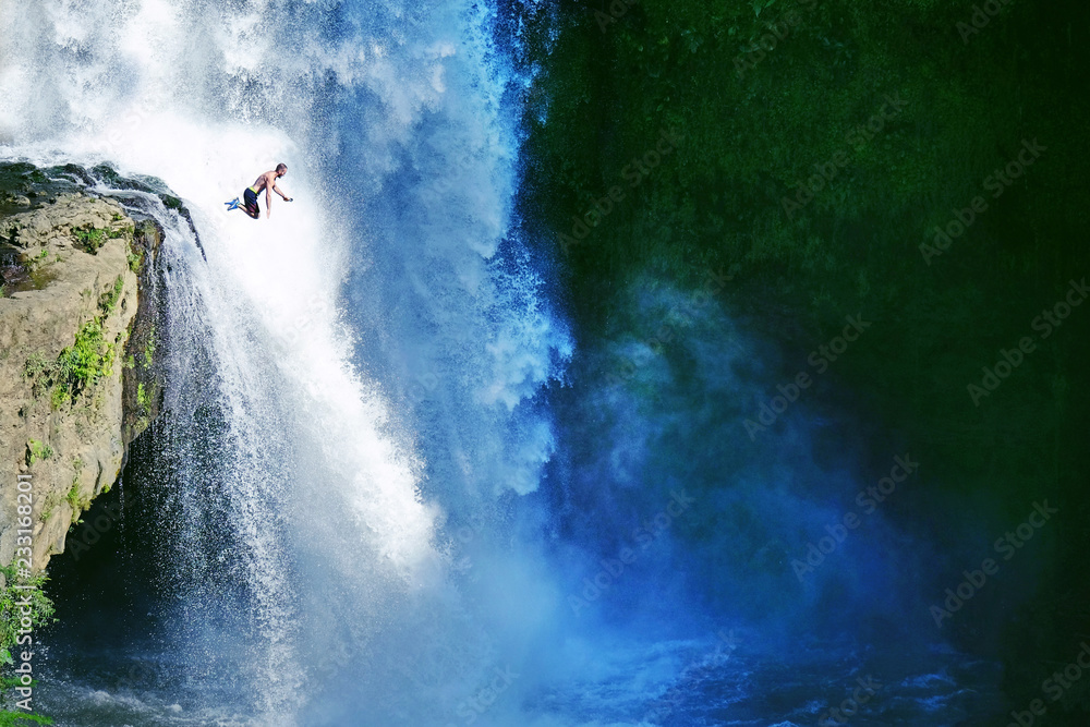 Jumping from the rock into the water. Man having fun at waterfalls in the nature. Bali, Indonesia