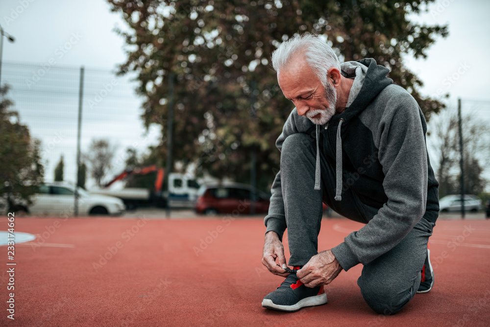 Senior man preparing for a run on outdoor stadium.