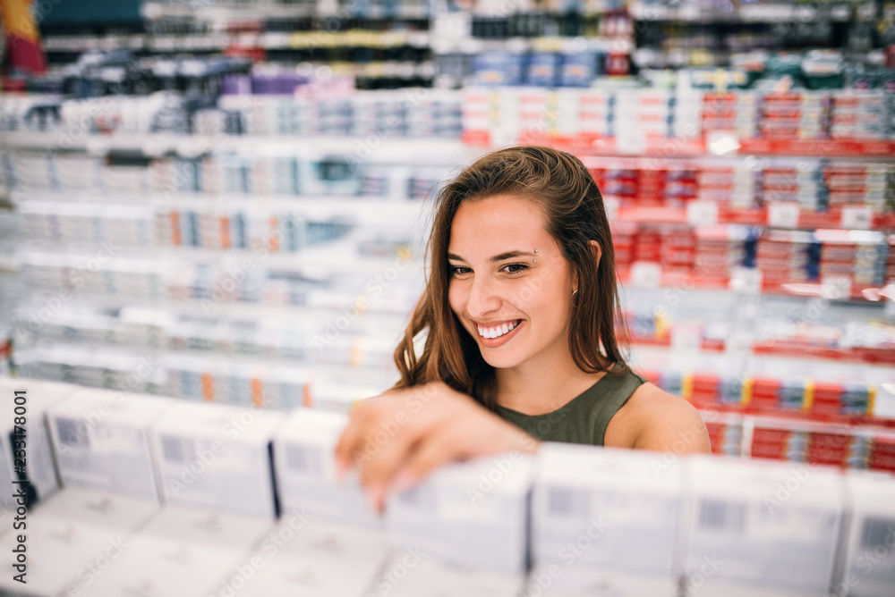 Smiling woman buying cosmetic in pharmacy store.