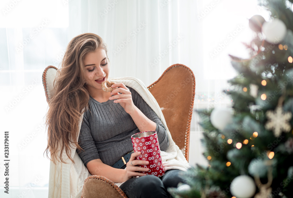 年轻漂亮女人在明亮的房间里吃圣诞饼干