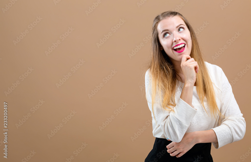 Young woman in a thoughtful pose on a brown background