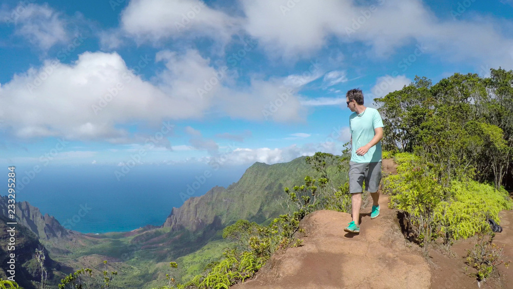 活跃的年轻人沿着郁郁葱葱的火山峡谷中的高山山脊徒步旅行