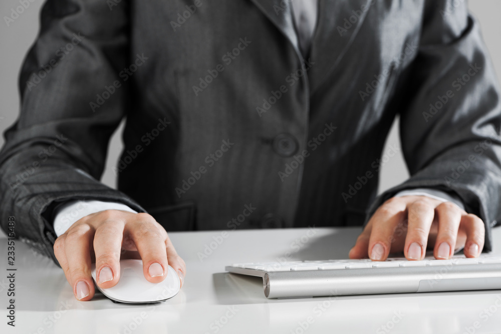 Closeup of businesswoman hand typing on keyboard with mouse on wood table