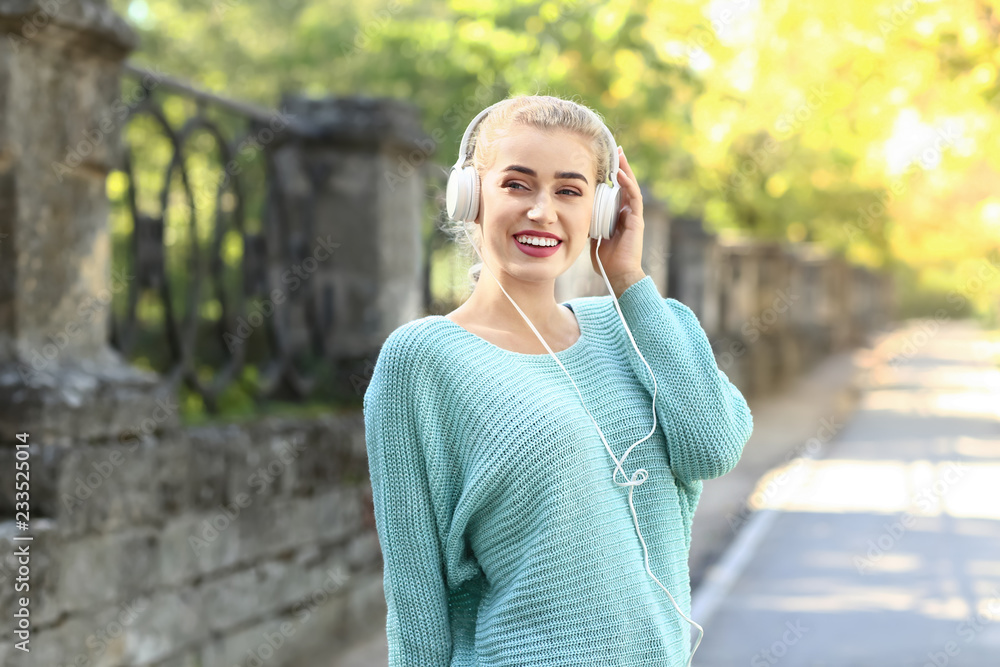 美丽的年轻女子在户外听音乐