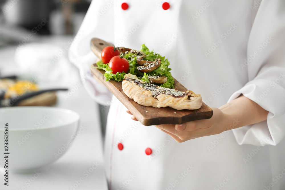 Young female chef with tasty dish in kitchen, closeup