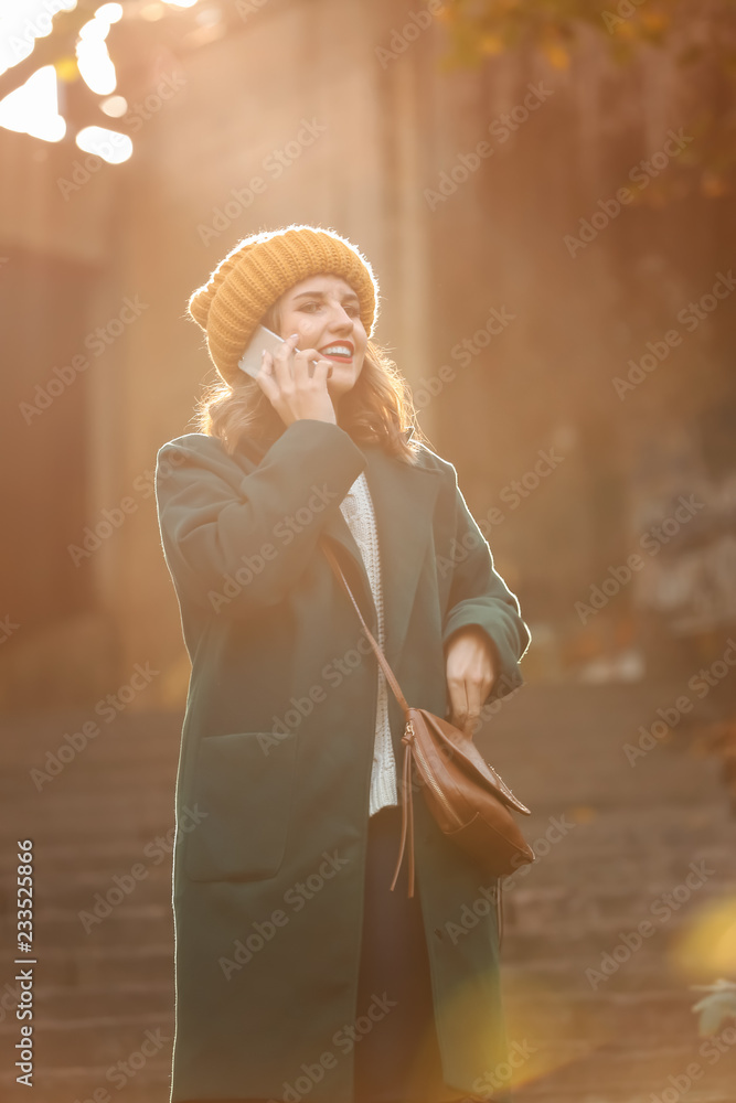 美丽的年轻女子在户外楼梯上用手机聊天