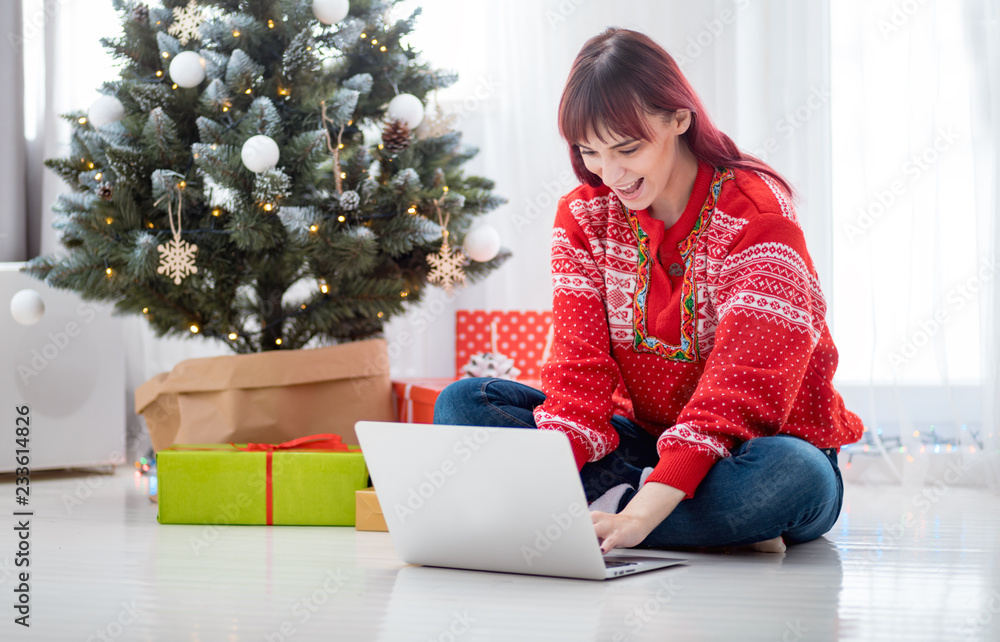 Young woman using laptop next to xmas tree, Christmas shopping online