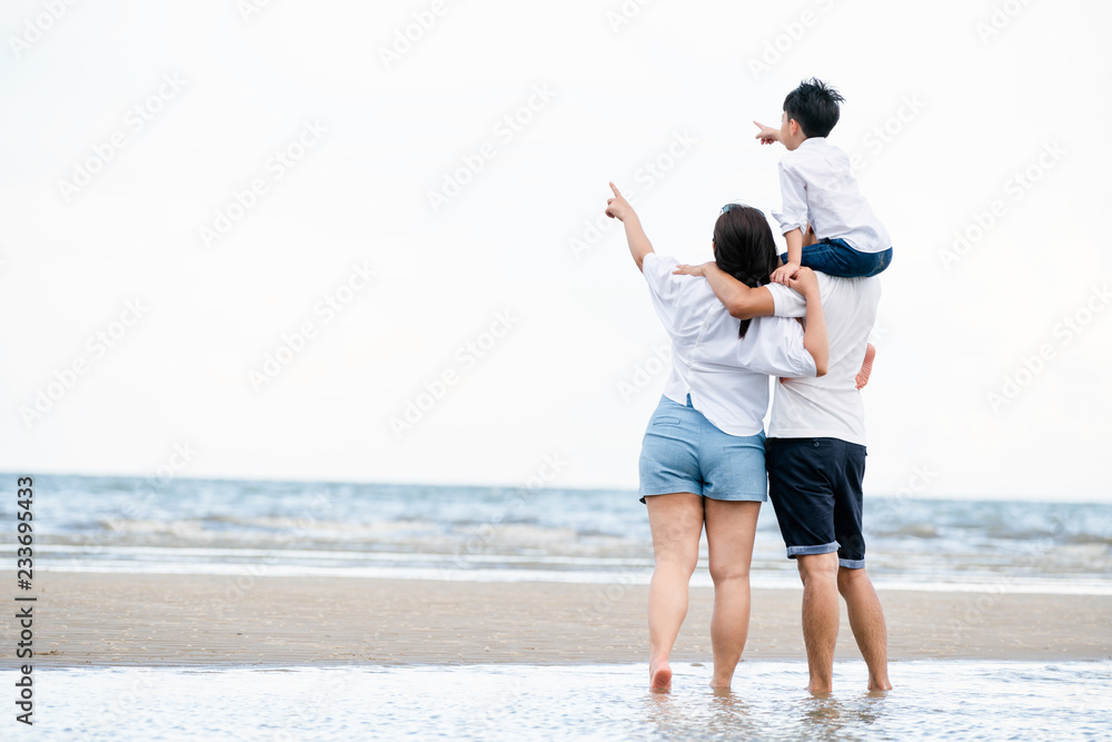 Happy family of father, mother and son goes vacation on a tropical sand beach in summer.