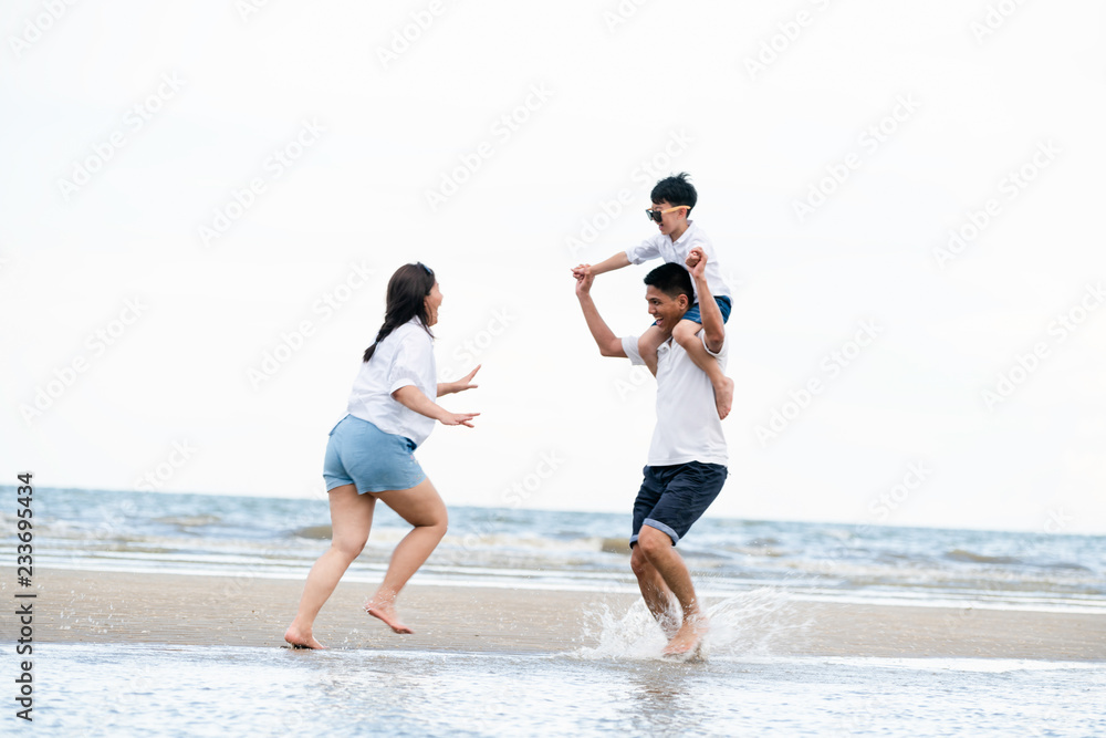 Happy family of father, mother and son goes vacation on a tropical sand beach in summer.