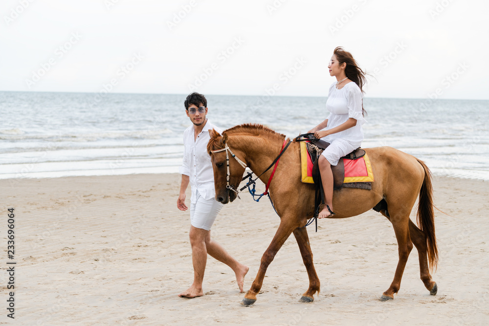 这对年轻夫妇暑假去海滩骑马度蜜月。