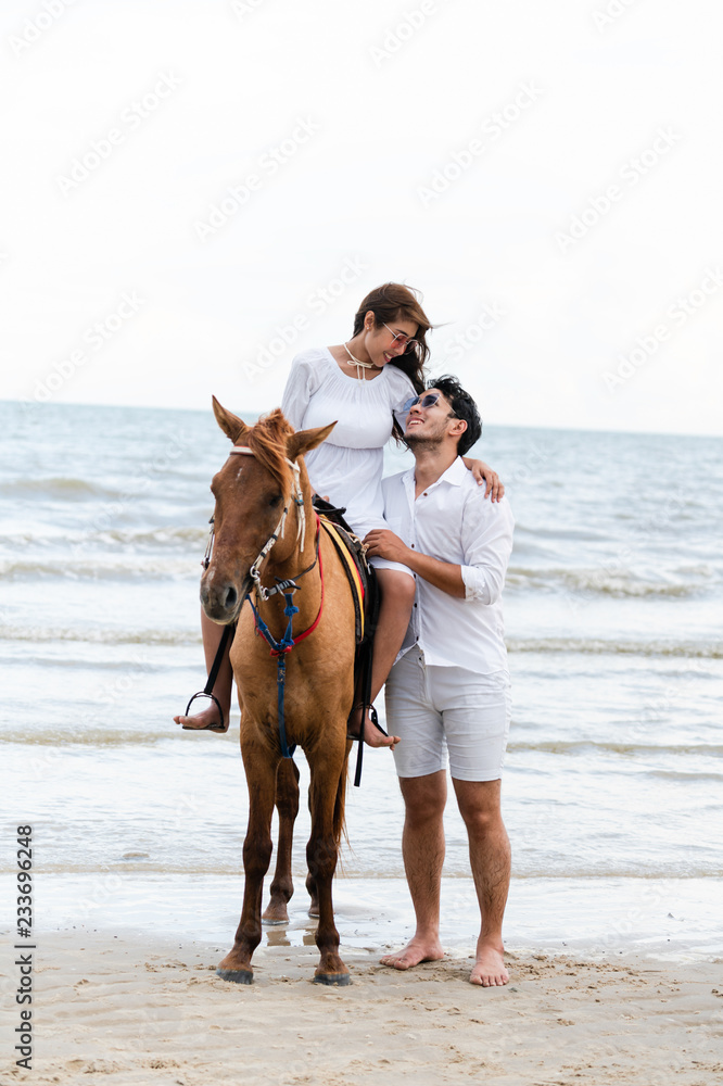 一对年轻夫妇暑假去海滩骑马度蜜月。