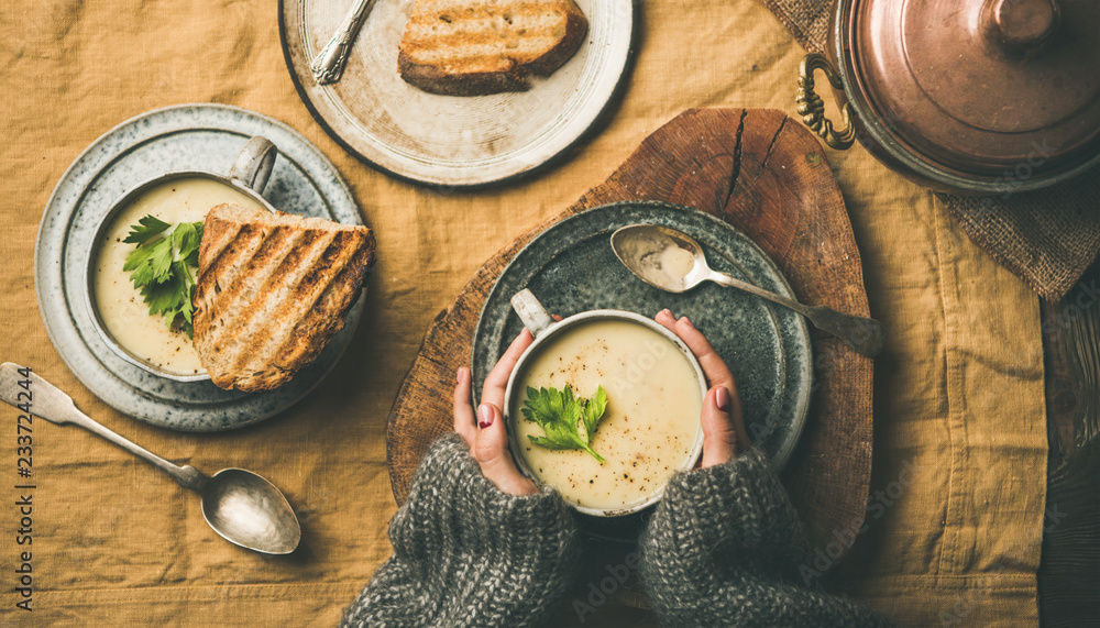 Autumn, Winter home dinner. Flat-lay of Fall warming celery cream soup in cups, grilled bread and fe