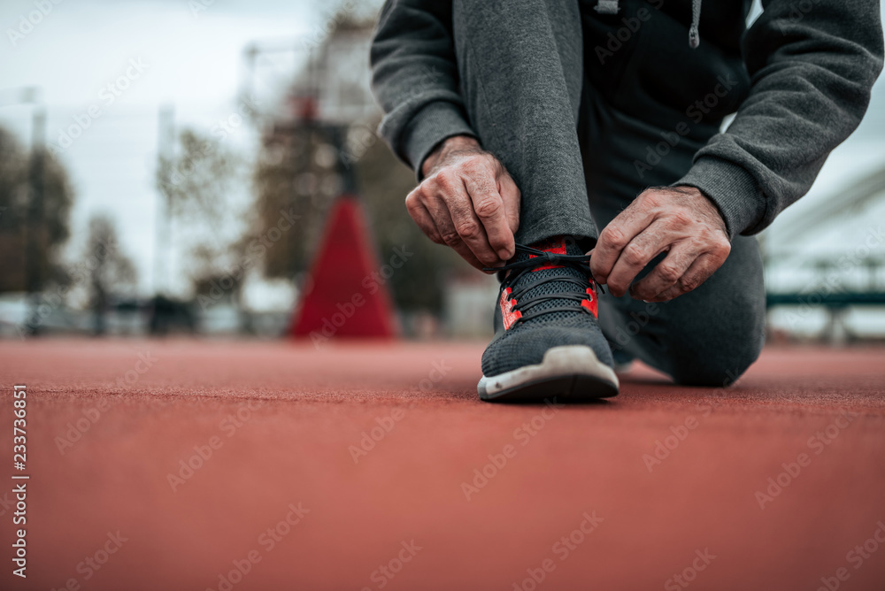 在体育场跑步前系鞋带。低角度图片。