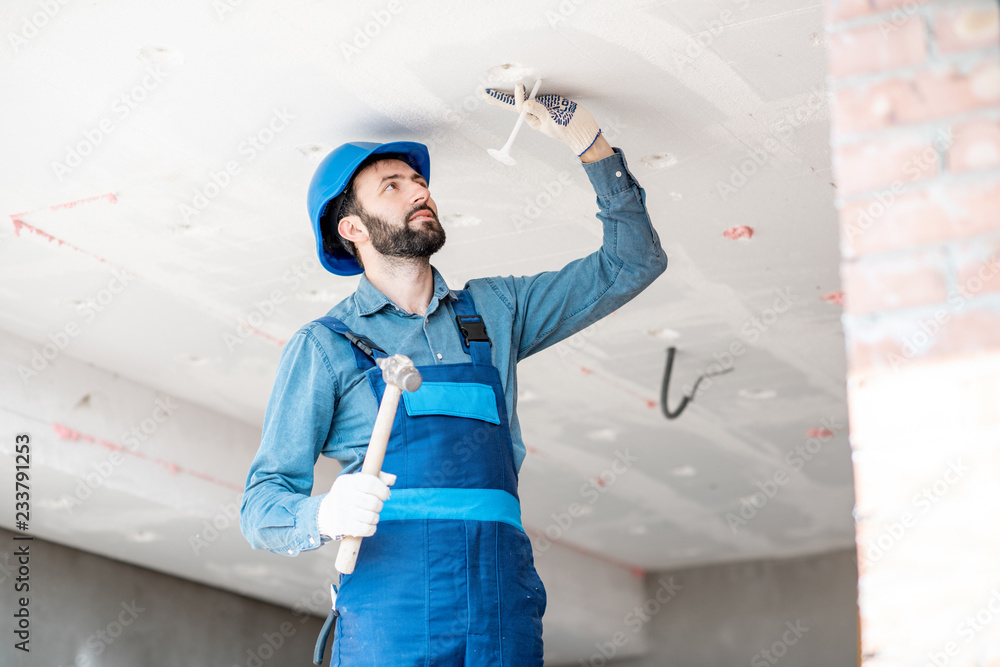 Builder warming building ceiling mounting foam panels on the construction site