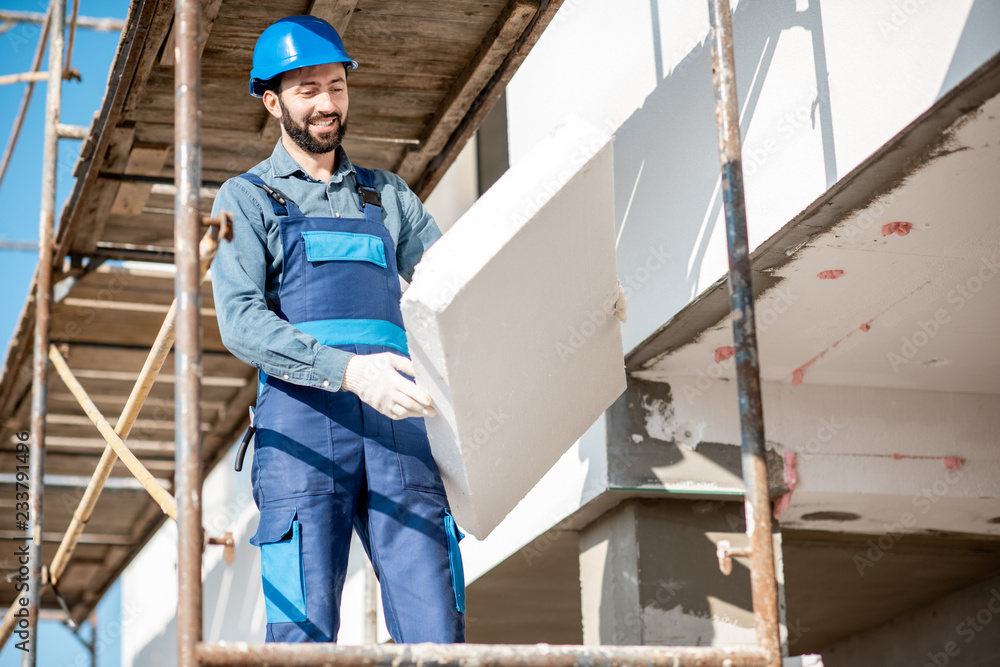 建筑工人用建筑脚手架上的泡沫板温暖建筑立面