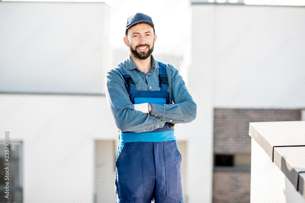 户外一栋新白色建筑的屋顶上，一位身穿制服的建筑工人的肖像