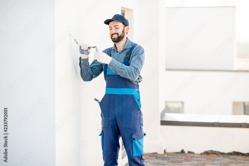 Builder mounting electric wiring on the building facade for outdoor lighting