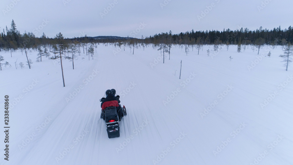 特写游客雪地摩托穿越白雪皑皑的冬季景观的后视图