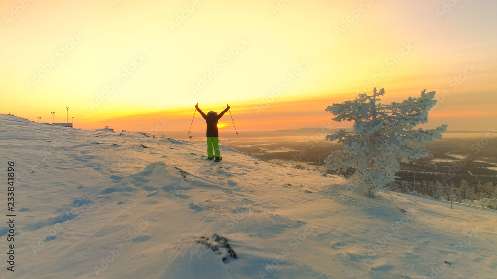 空中飞航活跃女子雪鞋雪撬雪山斜坡并在山顶举起双臂