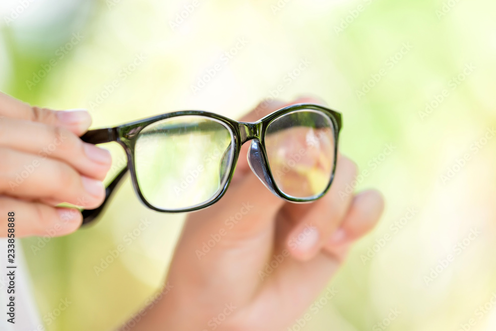 Woman holding the black eye glasses spectacles with shiny black frame on green background