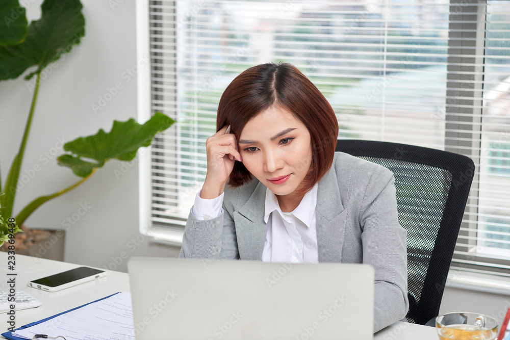 沮丧、压力重重、拿着笔记本电脑的年轻亚洲商界女性遇到麻烦