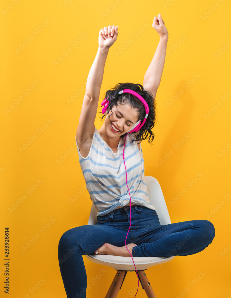 Young woman with headphones on a yellow background