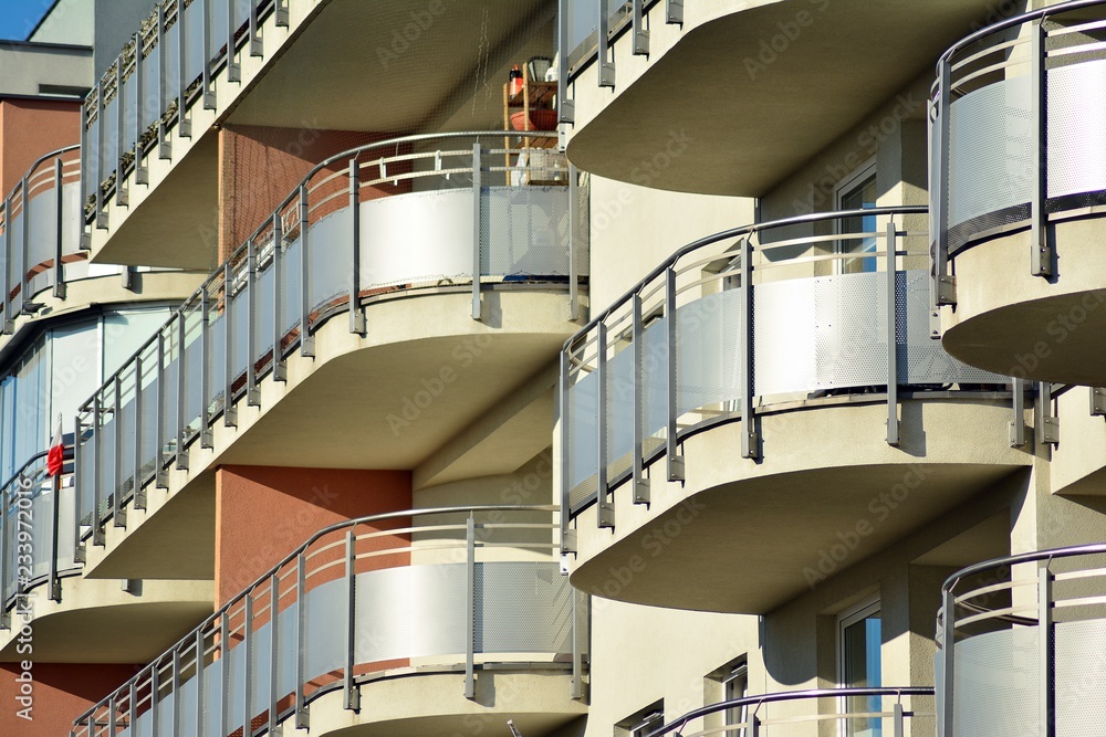 Fragment of a facade of a building with windows and balconies. Modern home with many flats.