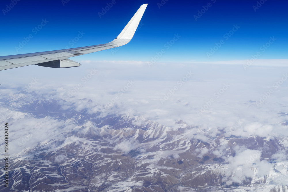 在中国西南部雪山上空飞行的飞机机翼。从飞机上俯瞰