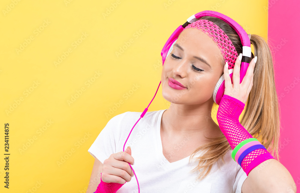 Woman in 1980s fashion with headphones on a split yellow and pink background