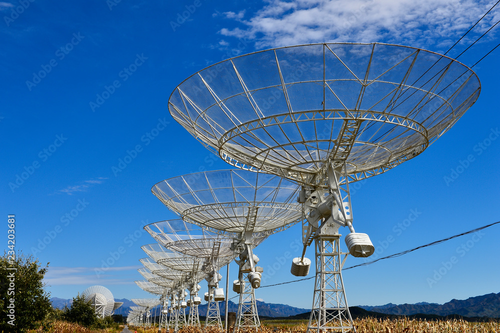 Array of satellite dishes or radio antennas against sky. Space o