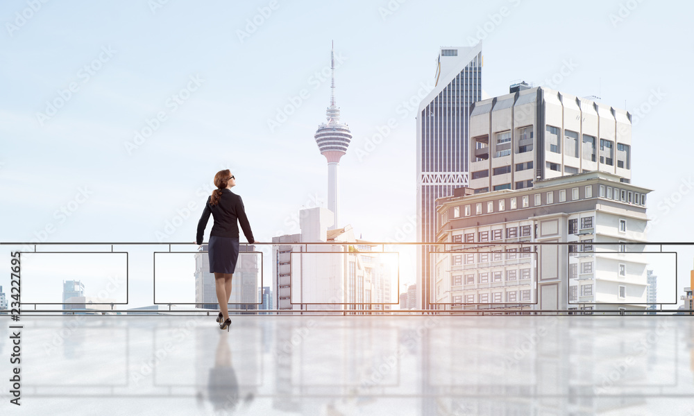 Sunrise above skyscrapers and businesswoman facing new day